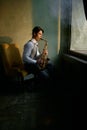 Jazz musician playing saxophone in front of window Royalty Free Stock Photo