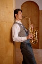 Jazz musician playing saxophone and leaning against art studio wall Royalty Free Stock Photo