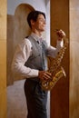 Jazz musician playing saxophone and leaning against art studio wall Royalty Free Stock Photo