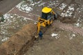 JCB excavator digs a trench for laying a sewer pipe. Worker of the water supply and Royalty Free Stock Photo