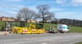 JCB style digger digging at the roadside surrounded by yellow barriers with Northern Gas Networks van and trailer