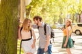 Jealous girl looking at flirting couple outdoor. Royalty Free Stock Photo