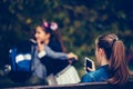 Jealous girl watching meet and hug two school friends while sitting on a bench outdoors