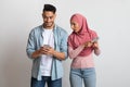 Jealous muslim woman in hijab looking at boyfriend's mobile phone, suffering mistrust Royalty Free Stock Photo