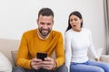 Jealous suspicious mad wife arguing with obsessed husband holding phone texting cheating on cellphone, distrustful girlfriend