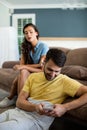 Jealous woman watching man using mobile phone in the living room Royalty Free Stock Photo