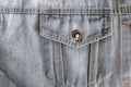 Jean pocket with a metal button in a denim light blue jacket close-up with coarse seams Royalty Free Stock Photo