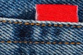 Jeans fabric, seam with orange threads and red sewn label, close-up macro view Royalty Free Stock Photo