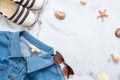 Jeans jacket, bottle of perfume and retro fashioned sunglasses on marble background. Flat lay design composition with feminine clo