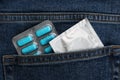 Jeans with pills and condom in pocket as background, top view. Potency problem concept Royalty Free Stock Photo