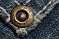 Jeans rivet, old dirty jeans, macro photo. Fashion jeans button. Sign JEANS JEANS on bronze part of button. Blue denim