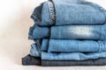 jeans are stacked on a white background. stack of several fashionable women`s or teenage casual all-season denim pants clothing b