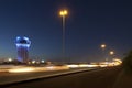 Jeddah water tower at night, with car lights motion on the street.