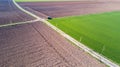 A jeep crossing a country road, off-road aerial view of a car traveling a dirt road through the fields.