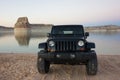 A jeep parked on the shores of lake powell