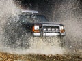 Jeep passes through the water creating large spray of water