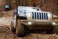 Jeep Rubicon JK climbing a hill on a muddy trail.