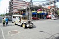 A Jeepney taxi drives down the street/road in downtown Manila with designs and colourful decorations on the vehicle