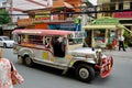A Jeepney taxi drives down the street/road in downtown Manila with designs and colourful decorations on the vehicle