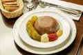 Jelly of meat with canned cucumbers and some spicy seasoning on the white plate. Menu of restaurant Royalty Free Stock Photo