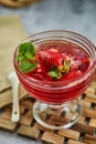 Jelly with strawberries in a glass on a wooden board, against a background of concrete Royalty Free Stock Photo