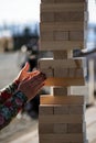 Jenga, girl`s hands try to pull out a wooden block, without tipp