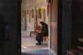 An elderly nun sits on a chair and reads a holy book in the Monastery Deir Hijleh - Monastery of Gerasim of Jordan, in the