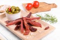 Jerky meat strips with spices, green olives, rosemary on wooden plate Royalty Free Stock Photo