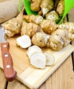 Jerusalem artichokes cut with knife and bucket on board