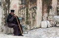 Jerusalem, Israel - 12/15/2019: african monk, priest sitting at wall of basilica