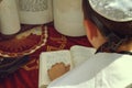 A rear view of praying young man hand with a tefillin holding a bible book, while reading a pray at a Jewish ritual Royalty Free Stock Photo