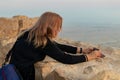 A young girl has prepared a mobile phone for a photo and is waiting for the sunrise on the fortress wall in the ruins of the