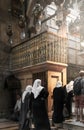 Believing women in white headscarves and in black clothes praying inside the Church of the Holy Sepulcher Temple of the Resurrec