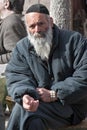 JERUSALEM, ISRAEL - MARCH 15, 2006: Purim carnival. Portrait of a tramp begging. An elderly man in a black jacket, kippa and beard