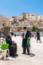 Two old Jewish orthodox men in black suits and hats drinking lemonade and talking near the entrance alley to the Western Wall