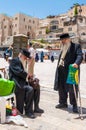 Two old Jewish orthodox men in black suits and hats drinking lemonade and talking near the entrance alley to the Western Wall