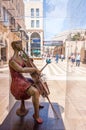 View on Mamilla road through street art sculpture of woman violoncellist playing on cello in glass box. Jerusalem, Israel