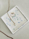Jesmonite handcrafted jewelry storage trinket square tray with blue green terrazzo effect, Golden ring and necklace on it