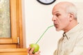 Jestful elder in kitchen, focused on apple