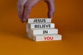 Jesus believe in you symbol. Concept words `Jesus believe in you` on wooden blocks on a beautiful orange background. Businessman