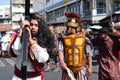 Jesus Christ carrying wooden cross admist cheering crowd, street drama representing the events that led to his Crucifixion