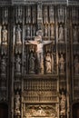 Jesus Christ on the cross in a cathedral or church interior surrounded by ornate stone carvings