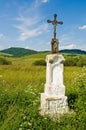 Jesus Christ on old wayside cross in meadow.