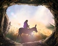 Jesus Christ riding donkey with tomb stone on meadow sunset Royalty Free Stock Photo