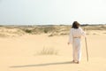 Jesus Christ walking with stick in desert, back view. Space for text