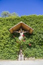 Jesus christ, wooden crucifix, spontaneous religiosity of the people in the midst of plants and roses Royalty Free Stock Photo