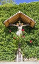 Jesus christ, wooden crucifix, spontaneous religiosity of the people in the midst of plants and roses Royalty Free Stock Photo