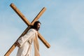 Jesus holding wooden cross against sky Royalty Free Stock Photo