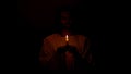 Jesus praying in darkness holding candle, expiation of sins, faith in salvation