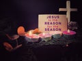 Jesus is the reason for the season on paper. Greating card with candles background. Christmas preparation or Advent concept. Royalty Free Stock Photo